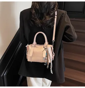 Detail of light pink embossed handbag with bear charm and decorative strap in a lifestyle setting