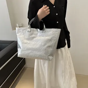 Dettaglio della borsa tote in carta Dupont argento con stampa TOTE BAG e texture a pieghe