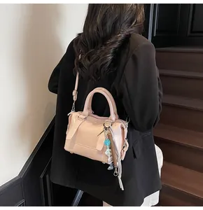 Close-up of light pink Boston handbag featuring CIHO 2AO embossed lettering and charm