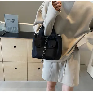 Detail of black nylon drawstring bucket bag showing front flap pocket and woven cord