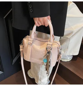 Detail of light pink patent leather boston bag with embossed text and trendy charms
