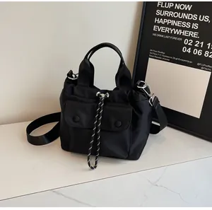 Detail view of black nylon bucket bag with dual front flap pockets and woven drawstring closure