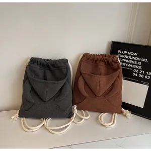 Detail of waffle fabric drawstring backpacks in dark gray and brown with hood pockets