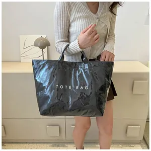 Dettaglio della borsa tote nera impermeabile con stampa TOTE BAG indossata dal modello