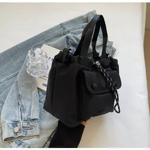 Detail of black oxford nylon bucket bag with drawstring closure and front pocket