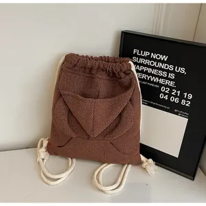 Detail of dark brown waffle texture drawstring backpack with white cotton rope straps