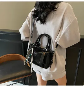 Close-up of black embossed handbag with sleek finish and braided strap details
