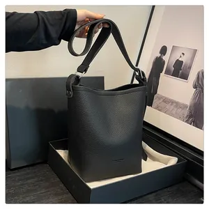 Close-up of black pebble leather bucket bag featuring adjustable strap and premium gift box