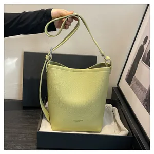 Detail of avocado green bucket bag with lychee grain leather and adjustable shoulder strap