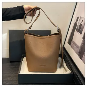 Detailed view of brown leather bucket bag with litchi texture and silver buckle strap