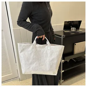 Dettaglio ravvicinato della borsa tote in carta DuPont con superficie strutturata e testo inciso