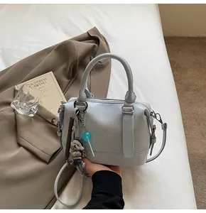 Detail view of light blue leather handbag with letter embossing and cute bear charms