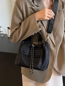 Versatile black nylon drawstring bucket bag with flap pocket and adjustable shoulder strap
