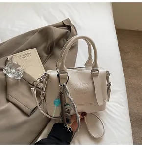 Detail of cream embossed handbag featuring decorative bear charms and logo texture