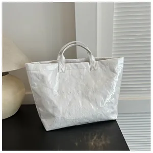 Dettaglio di una borsa tote in carta DuPont bianca con texture stropicciata e goffrata