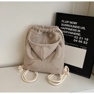 Detail of waffle-textured beige drawstring backpack featuring a unique hoodie pocket design