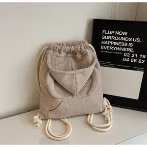 Close-up of beige waffle knit backpack with hoodie design and drawstring straps