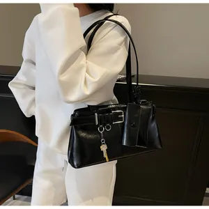 Detail of black glossy leather shoulder bag with decorative buckle and mini pouch accessory
