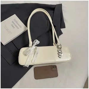 Détail du sac baguette crème avec noeud en dentelle et breloque coeur en métal