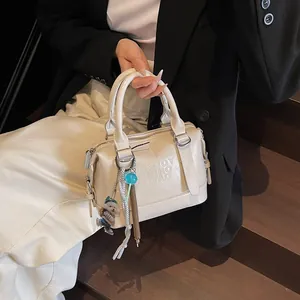 Chic beige embossed handbag with bear pendant shown on model in minimalist style