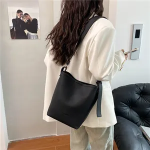 Minimalist black lychee texture bucket bag with wide shoulder strap for casual commuting