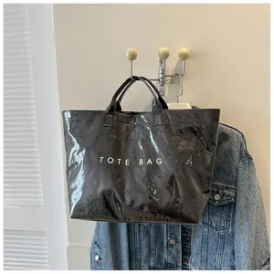 Borsa tote nera lucida con stampa bianca appesa accanto a una giacca di jeans