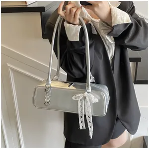 Détails du sac baguette argenté métallisé avec nœud en dentelle et pendentif cœur