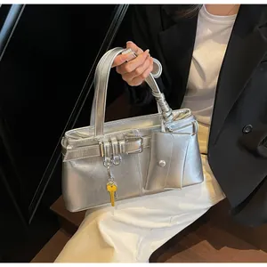 Detail of silver metallic handbag with mini pouch and yellow key charm on a model