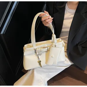Detail of off-white faux leather shoulder bag with gold key and mini card case