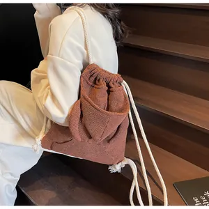 Detail of brown waffle knit drawstring backpack with white ropes on a model