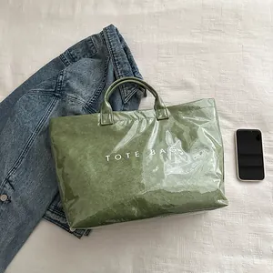 Vista piatta della borsa tote in carta verde retrò con testo bianco e accessori
