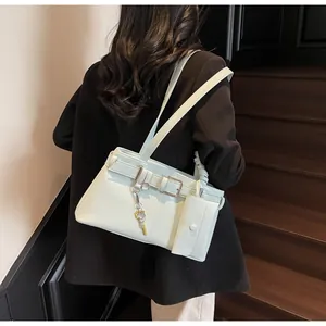 Detail of mint green biker bag with decorative belts and mini charm on black blazer