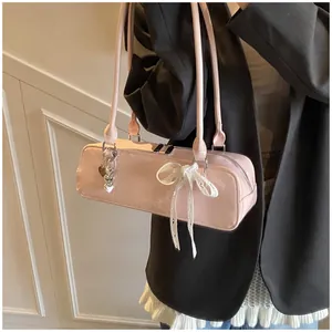 Sac baguette rose en cuir verni avec nœud en dentelle blanche et pendentif cœur
