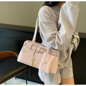 Detail of light pink moto-style shoulder bag featuring silver buckle and gold key charm