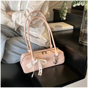Détail du sac en cuir verni rose avec nœud en dentelle blanche et pendentif cœur