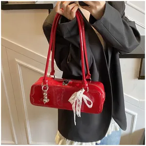 Détail du sac sous le bras en cuir verni rouge avec fermetures éclair et nœud en dentelle