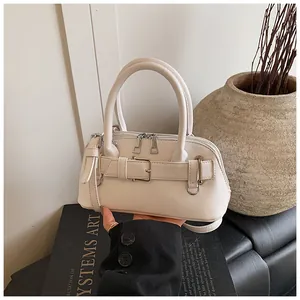 Close-up of off-white shell bag with silver hardware and decorative buckle detail