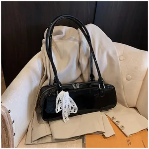 Détail d'un sac baguette en cuir verni noir avec dentelle blanche et fini brillant miroir