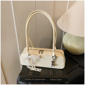 Détail du sac à bandoulière minimaliste crème avec pendentif ours argenté et fini lisse