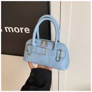 Detail of light blue shell handbag with decorative belt buckle and dual metal zippers