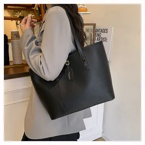 Black large capacity tote bag with lychee texture shown on a female model in a cafe