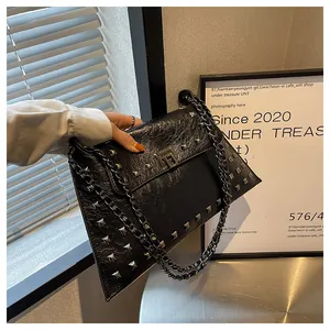 Détail d'un sac à bandoulière noir avec rivets carrés argentés et bandoulière en chaîne