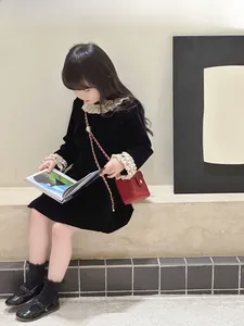 Fille en robe de velours noir avec un mini sac boîte rouge sur des marches en pierre