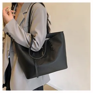 Detail of black pebbled leather tote bag with dual straps and fashion tag detail