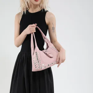 Borsa a spalla rosa in pelle con borchie argentate indossata da una modella elegante