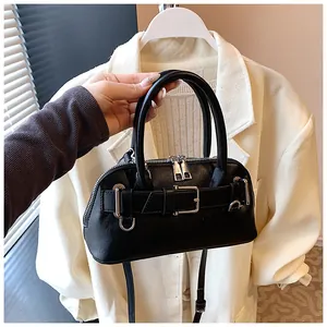 Detail of black leather shell bag with silver zippers and stylish belt buckle decor