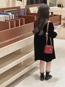 Détail du petit sac rouge matelassé avec chaîne dorée sur une robe en velours rétro