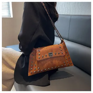 Détail d'un sac porté épaule marron vintage avec rivets et bandoulière chaîne