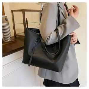Detail of black pebbled leather tote bag showing golden logo and shoulder strap texture