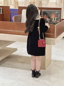 Détail d'un enfant en robe de velours à dentelle blanche et mini sac à chaîne rouge